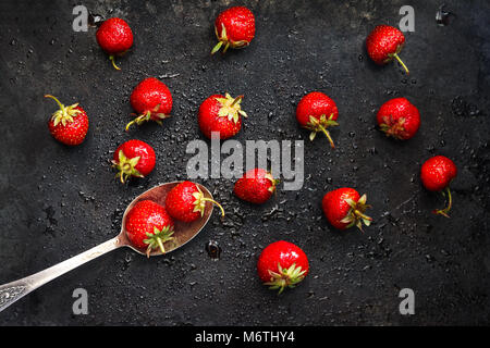 in a spoon a wet strawberry on a dark background with splashes of water, top view. Stock Photo