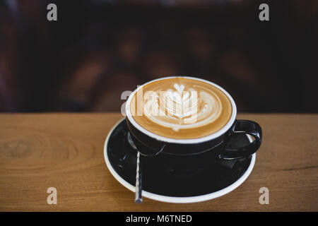 Beautiful latte art coffee on wood table in coffee shop Stock Photo