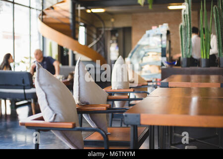 Empty chair with pillow and wood table in coffee shop with blured background Stock Photo