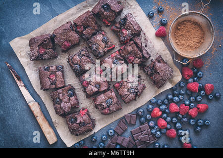 Homemade Chocolate raspberry and blueberry brownies with ingredients on a slate background. Stock Photo