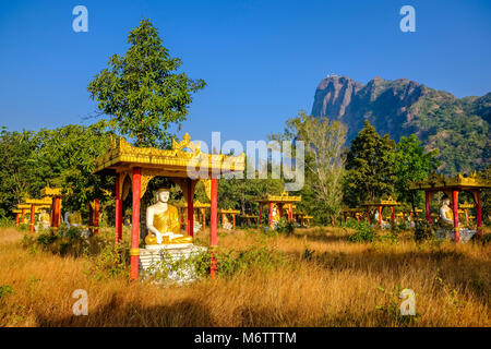 Buddha statues of Lumbini Garden, sheltered by a colorful wooden roof, with Mt. Zwegabin in the distance Stock Photo