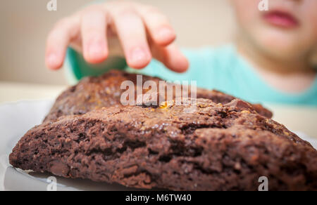 Child hand reaching for chocolate sweets. Concept of unhealthy food for children. Happy careless childhood or child's dream concept. Stock Photo