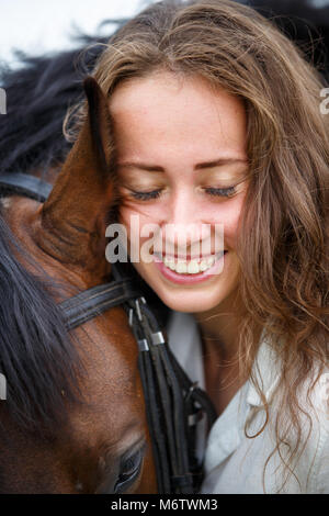 Young happy rider woman with her bay horse. Portrait of smiling girl with her stallion Stock Photo
