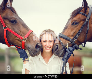 Young rider girl having fun with two her horses. Equestrian sport concept background Stock Photo