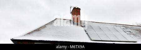 Solar energy panels on a roof covered in snow Stock Photo