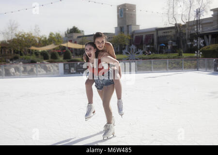 Two teen girl friends goofing off on an outdoor ice rink ...