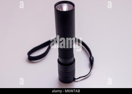 Torch with hand strap isolated on white background. LED aluminium flashlight. Black torch. Stock Photo
