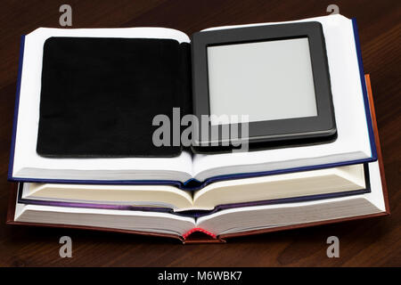 E-book reader device on desk in library. Alternative for traditional books. Stock Photo
