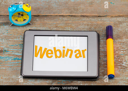 Webinar -  inscription on tablet screen. Alarm clock with tablet  on wooden background. Webinar, business concept. Stock Photo