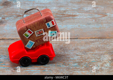 red toy car with suitcases on a wooden background. Travel concept. With copy space. Stock Photo