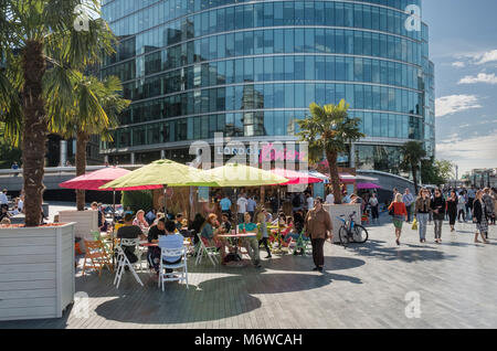 People sitting in summer sunshine at the London Riviera pop up restaurant on the Southbank, London, UK