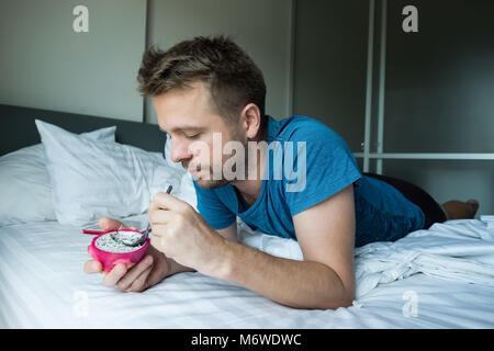 caucasian man eating dragon fruie with spoon in the bed. Stock Photo