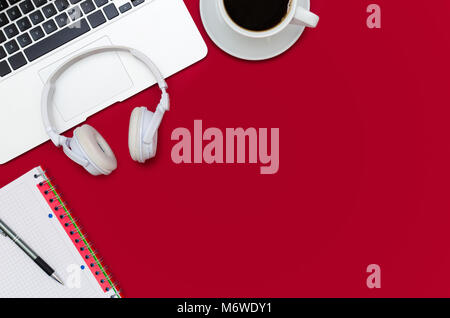 Office desk table with laptop, smartphone, and cup of coffee. Flat lay with copy space on red background Stock Photo