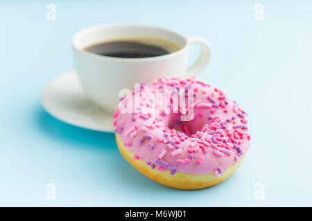 Pink donut and coffee cup on blue background. Stock Photo