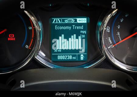 Car dashboard gauge screen showing fuel economy trend in miles per gallon with speed and rev counters Stock Photo