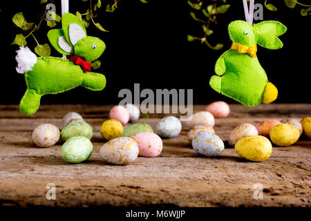 Handmade easter rabbits and eggs on wooden table. Black background. Stock Photo
