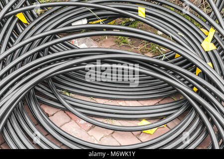 rolled up plastic cables lying on brick floor Stock Photo