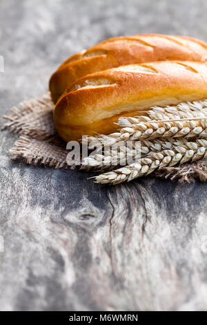 Small  loafs and ears of wheat on sackcloth napkin Stock Photo