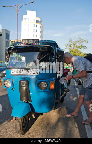 Vertical view of a western tourist hailing a rickshaw in Colombo, Sri Lanka. Stock Photo