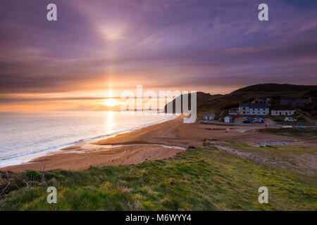 Seatown, Dorset, UK. 6th March 2018.  UK Weather.   A beam of sunlight shines up on the high level clouds which are partially obscuring the sunset at Seatown on the Jurassic Coast of Dorset.  In the picture is the historic pub the Anchor Inn.  Picture Credit: Graham Hunt/Alamy Live News Stock Photo