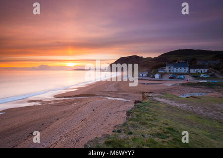 Seatown, Dorset, UK. 6th March 2018.  UK Weather.   High level clouds partially obscures the sunset at Seatown on the Jurassic Coast of Dorset.  In the picture is the historic pub the Anchor Inn.  Picture Credit: Graham Hunt/Alamy Live News Stock Photo