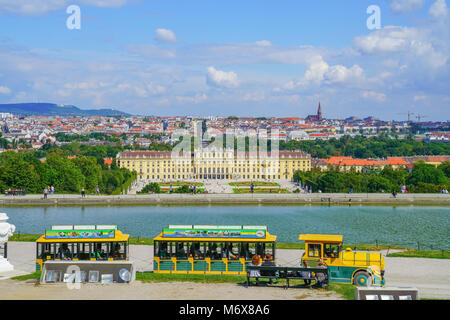 VIENNA,AUSTRIA - SEPTEMBER 4 2017; Schonbrunn Palace with city of Vienna beyond and pond from Gloriette hill with yellow tourist train in foreground Stock Photo