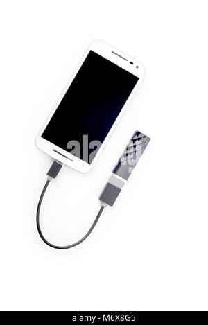 White smartphone connected to a black USB key with an OTG cable. Isolated on white background Stock Photo