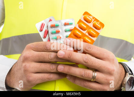 Constructor or builder hands holding pills capsules blisters as stressful and dangerous profession Stock Photo