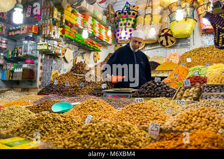 A vendor selling and weighing nuts out of his stall in the Old Medina souqs in Marrakesh, Morocco Stock Photo