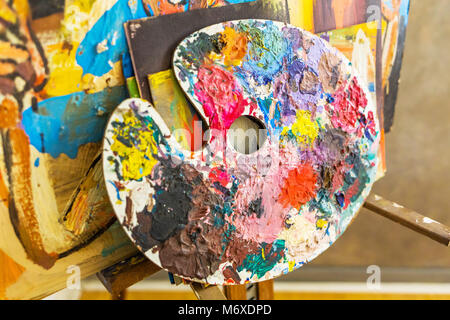 Palette with various paint colors near canvas close up Stock Photo