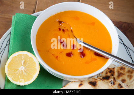 A traditional Turkish meal of Red lentil soup with flatbread and Lemon wedge, Kirmizi mercimek corbasi. Stock Photo
