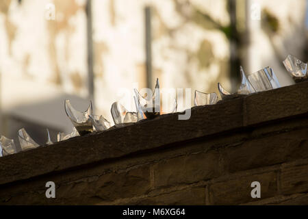 Broken bottles set in cement on the top of a wall to deter thieves or intruders Lancashire England UK GB Stock Photo