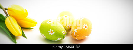 Three easter eggs with yellow tulips Stock Photo