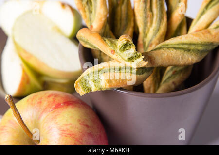 Cheese and pesto twists a cup with apples Stock Photo