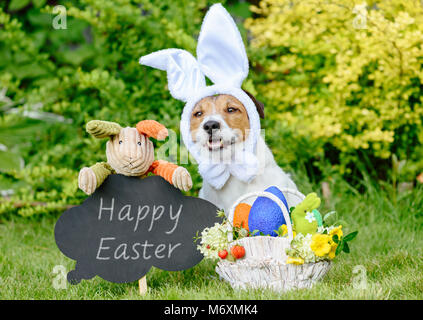 Easter greeting with three bunnies,  basket of colored eggs and blackboard Stock Photo