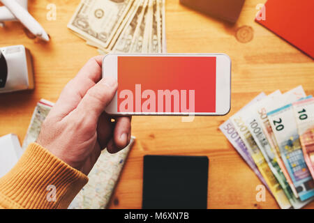 Travel app for mobile phone mock up screen, overhead view of male hand using smartphone with blank screen as copy space Stock Photo