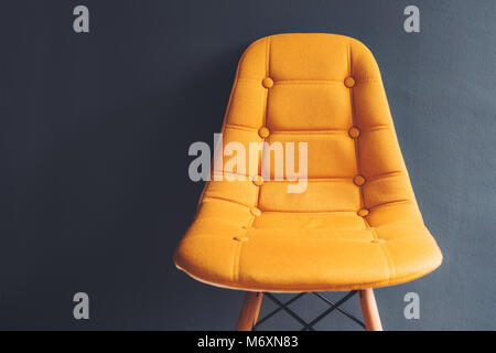 Empty generic yellow chair against gray wall of waiting room interior, minimalist composition with copy space Stock Photo