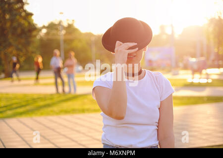 Beautiful woman hiding face behind hat showing eyes Stock Photo
