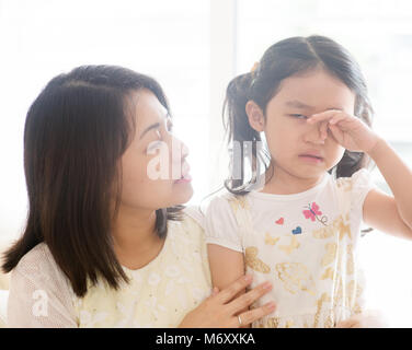 Mother comforting crying daughter. Asian family at home, living lifestyle indoors. Stock Photo
