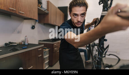 Worker fixing a bicycle in workshop. Man working on a bicycle in a repair shop. Stock Photo