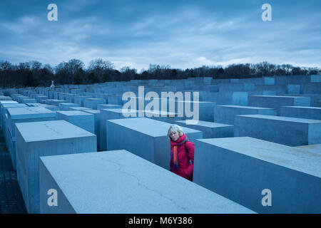 A lady in red in amongst the Holocaust Memorial, Mitte, Berlin, Germany Stock Photo