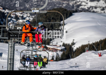 A male ski instructor speaks to a woman on a chairlift in the French Alpine resort of Courchevel. Stock Photo
