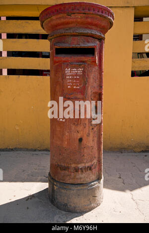 Vertical close up of a rusty but functioning red British pillar box in Colombo, Sri Lanka Stock Photo