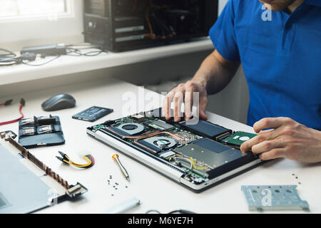 computer repairman installing new hard disk drive in laptop Stock Photo