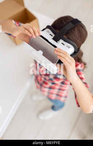 Top view of pre-teen girl inserting phone in VR headset Stock Photo