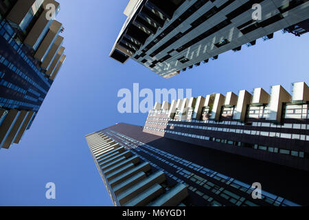 One point perspective looking straight up towards clear blue sky from ground level of tall skyscraper buildings in Milan, Italy Stock Photo