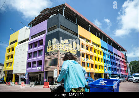 The central markets, Kuala Terengganu, Malaysia known as Pasar Besar Kedai Payang.  A woman cycles infront of colourfully painted building Stock Photo