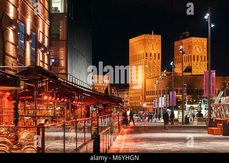 Night city view of Oslo, Norway at Aker Brygge Dock with restaurants and City Hall or Radhuset on background. Stock Photo