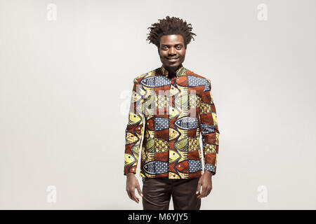 Happiness african man in traditional clothes toothy smile. Indoor, isolated on gray background Stock Photo