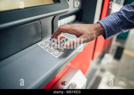 Close up shot of a businessman's hand pressing keys on a cash machine to get money out. Stock Photo